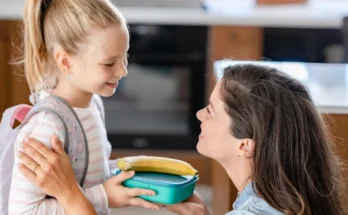 A woman handing a lunchbox to her daughter | Source: Shutterstock