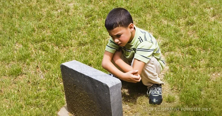 Sad Boy Near Grave. | Source: Getty Images