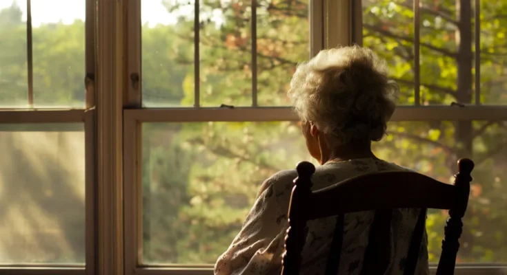 Elderly woman looking at the window | Source: Midjourney