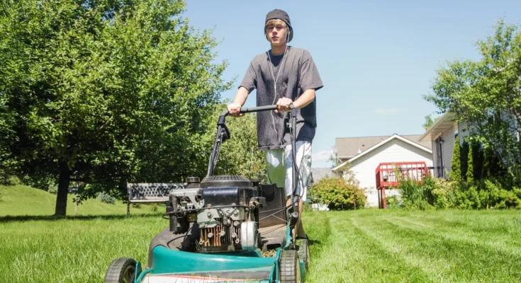 A teenage boy mowing a lawn on a sunny afternoon | Source: Shutterstock