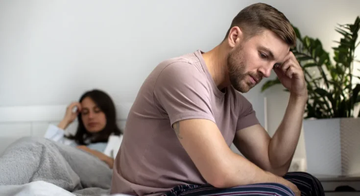 An upset couple sitting on a bed | Source: Freepik