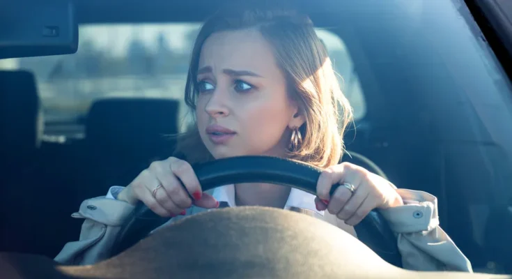 A young woman gripping the steering wheel, staring ahead with wide, anxious eyes | Source: Shutterstock