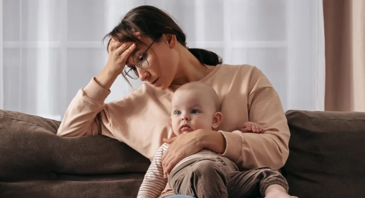 A stressed woman with a baby | Source: Shutterstock
