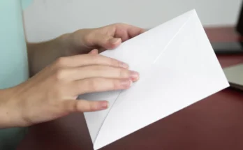 A woman holding a sealed white envelope | Source: Freepik