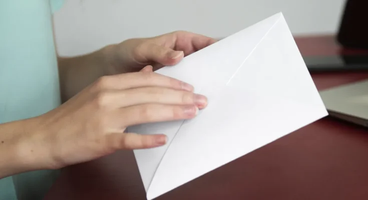 A woman holding a sealed white envelope | Source: Freepik