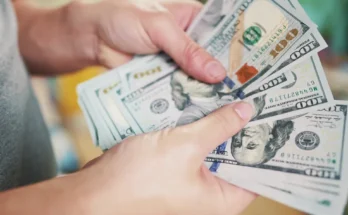 A person holding and counting a stack of $100 bills | Source: Shutterstock