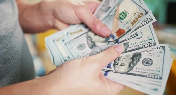 A person holding and counting a stack of $100 bills | Source: Shutterstock