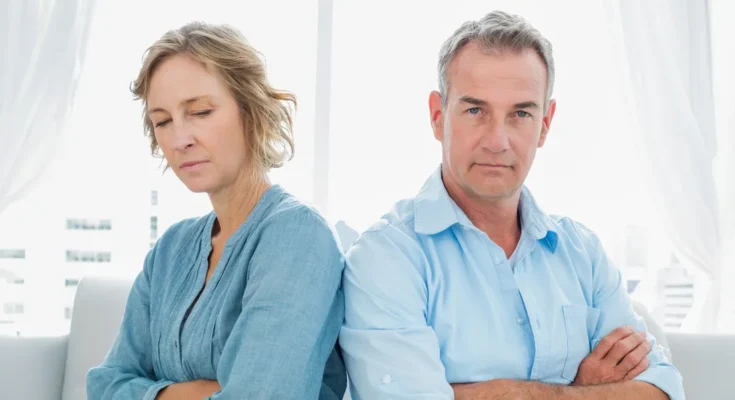 A tensed middle-aged couple sitting with arms crossed | Source: Shutterstock