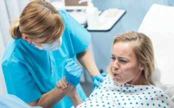 A woman holding a nurse's hand in a hospital room | Source: Shutterstock