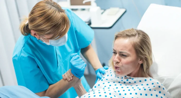 A woman holding a nurse's hand in a hospital room | Source: Shutterstock