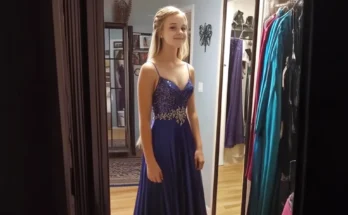 Teen girl in a sparkly blue dress, smiling in front of a mirror | Source: Getty Images