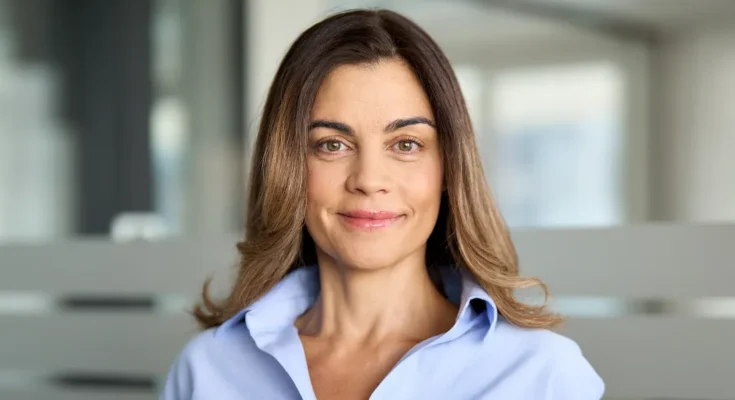A smiling middle-aged woman standing in a modern office building | Source: Shutterstock