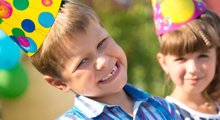 Kids enjoying a cheerful moment in party hats and sunshine | Source: Shutterstock