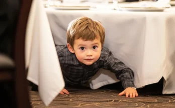A child crawling out from under a table | Source: The Celebritist