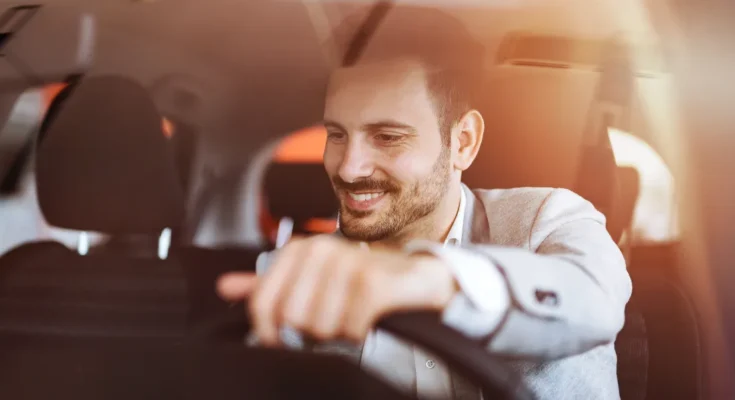 A smiling man sitting behind the wheel, enjoying the drive in his car | Source: Shutterstock