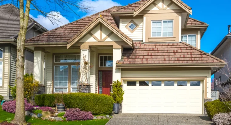 A suburban home with a red front door, manicured landscaping, and a bright, welcoming exterior | Source: Shutterstock