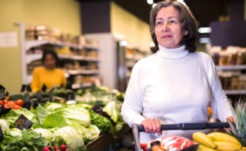 A senior woman grocery shopping in the produce section | Source: Shutterstock