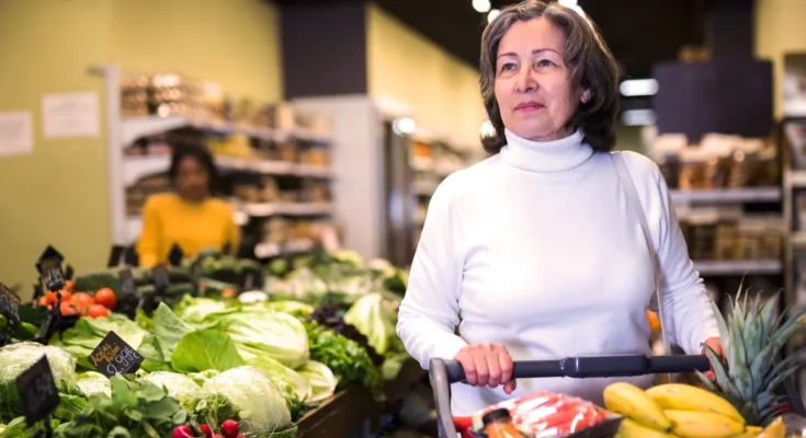 A senior woman grocery shopping in the produce section | Source: Shutterstock