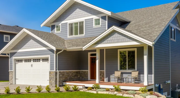 A modern two-story gray Craftsman-style home with a covered front porch and well-kept landscaping | Source: Shutterstock