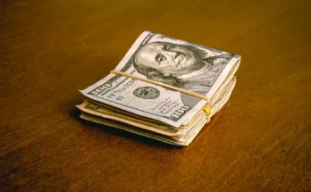 A folded stack of dollar bills on a table | Source: Shutterstock