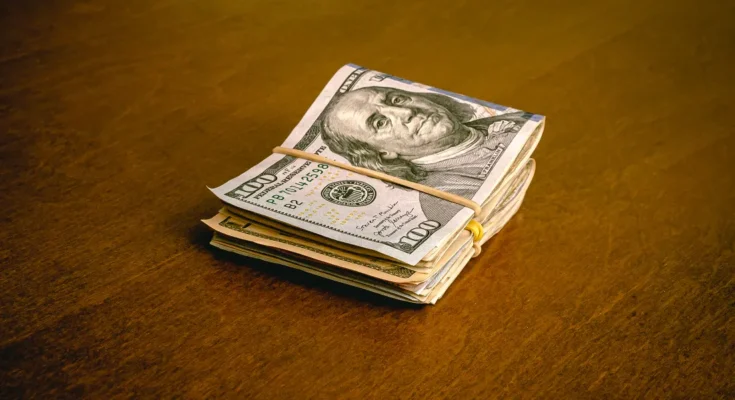 A folded stack of dollar bills on a table | Source: Shutterstock