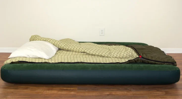An air mattress with a sleeping bag and pillow laid out on a hardwood floor | Source: Shutterstock