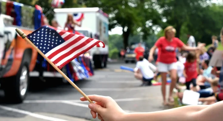 A person waving an American flag during a lively 4th of July parade | Source: Shutterstock