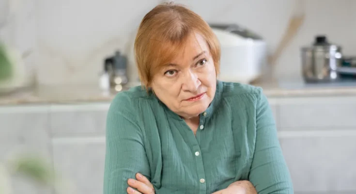 An unimpressed older woman sitting with her arms crossed | Source: Shutterstock