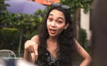 Young woman pointing and speaking with animated expression outdoors | Source: Shutterstock