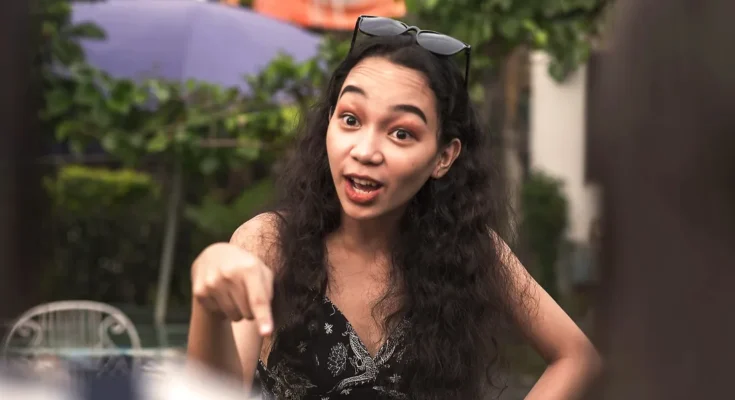 Young woman pointing and speaking with animated expression outdoors | Source: Shutterstock