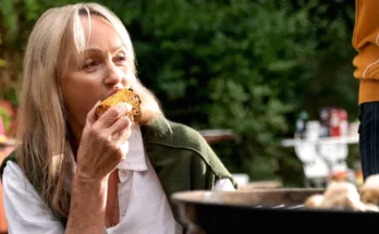 A woman enjoying grilled corn at an outdoor gathering | Source: Freepik