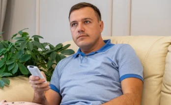 A man sitting on the couch and holding a TV remote | Source: Shutterstock