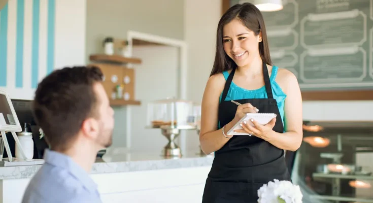 A man speaking to a smiling waitress | Source: Shutterstock