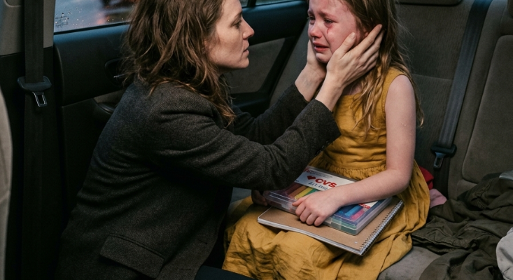 Woman holds girl's face